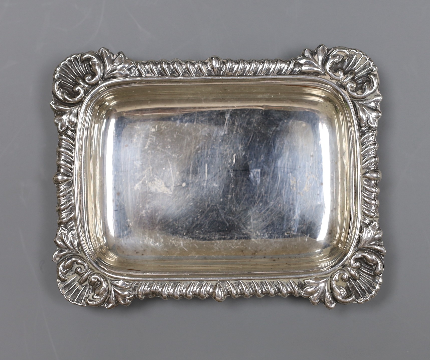 A late Victorian repousse silver 'Mr Punch' pin-tray, 10 x 8cm., Saunders & Shepherd, Birmingham, 1894, 10.7cm, one other silver dish, a silver mounted toilet jar and a plated small dish.